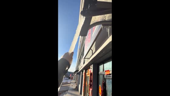 Man carefully removes icicle attached to roof shed in Heilongjiang, China