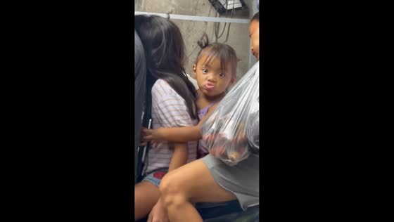 Mischievous girl makes funny faces while riding on a motorcycle in Tondo, Manila, Philippines