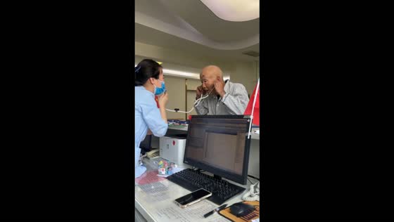 Hospital staff helps an elderly man hear by using a stethoscope in Jinan, China