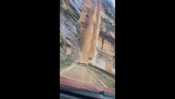 Driver passes through cascading floodwater on mountain road in Sichuan, China