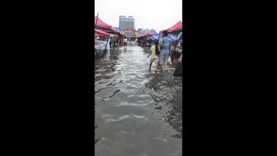 Flooded street market remains open as people walk through ankle-deep water in Beijing, China