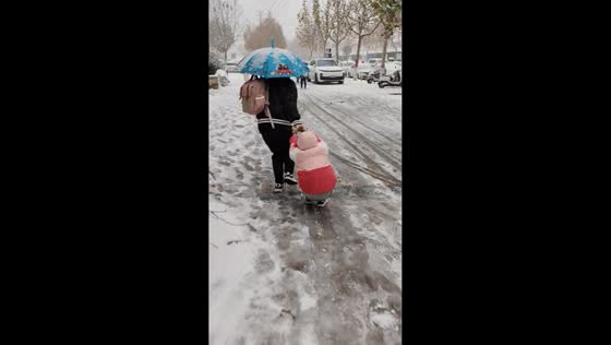 Father and daughter slip and fall while sliding on snow in Henan, China