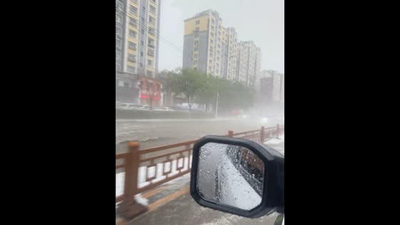 Car drives through flooded road during heavy rain in Liaoning, China