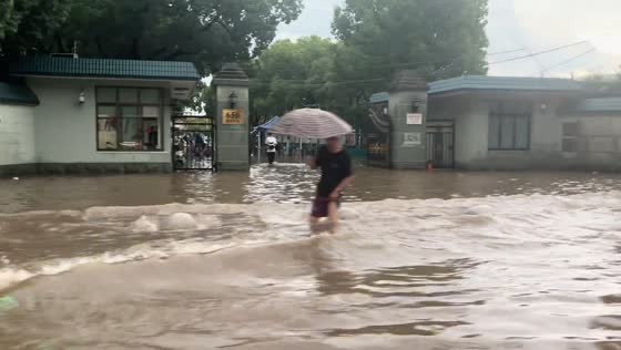 Residents wade through rushing floodwaters in Shanghai, China
