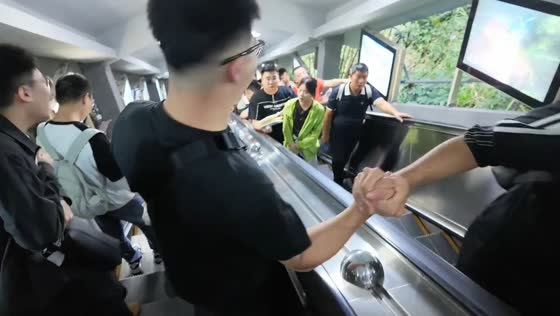 Strangers exchange a handshake across opposite-moving escalators in Guizhou, China