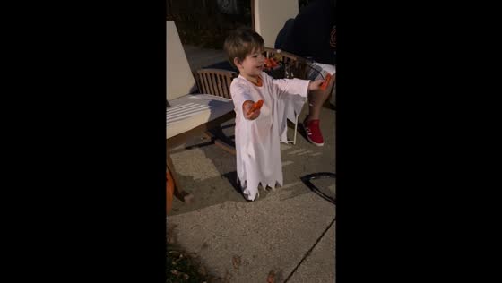 A Boy in a ghost costume hands out candy to no one on Halloween