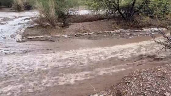 Floodwaters flow like a river after rain in driveway in Pinal, Arizona