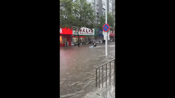 Severe flooding leaves pedestrians wading through waist-deep water in Dandong, China