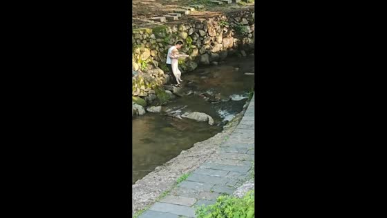 Man accidentally drops dog into a creek after slipping on rocks in Jiangxi, China