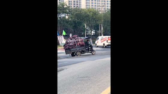 Overloaded electric tricycle struggles to move in Shaanxi, China