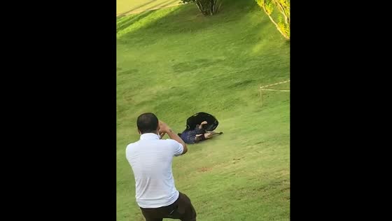 Two ladies fall while sliding on grass in Kanchanaburi, Thailand