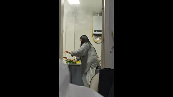 Woman cooks while heavy steam fills kitchen in Zhejiang, China
