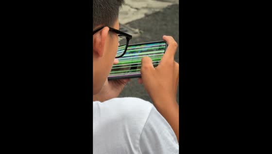 Boy plays mobile games on cracked screen in Hainan, China