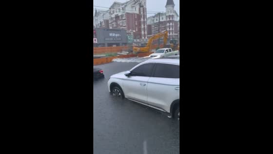 Cars drive through flooded road in Liaoning, China