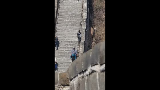Woman slides down handrail before stopping near passerby on Badaling Great Wall in Beijing, China