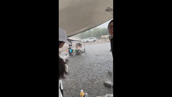 Campers hold onto tent as heavy rain and strong winds flood campsite in Shanxi, China