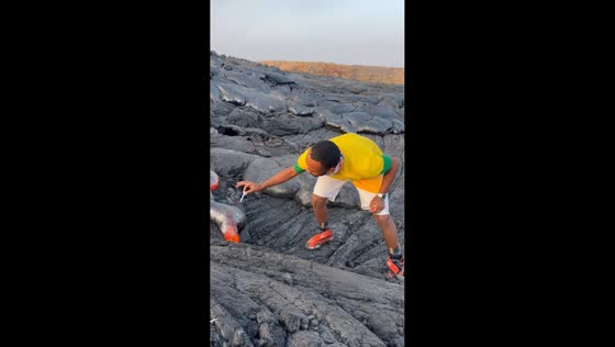 Man lights cigarette on molten lava from Erta Ale volcano in Afar, Ethiopia