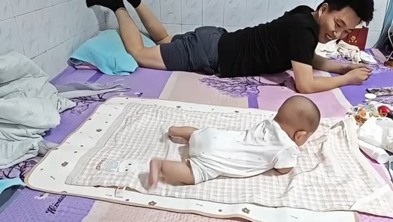 Baby imitates father while practicing rolling over in Shaanxi, China