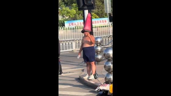 Topless boy wearing traffic cone poses on street in Tianjin, China