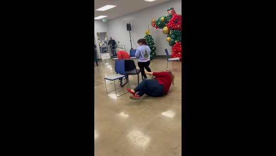 Woman slips during musical chairs at Christmas event in Los Angeles, California, USA