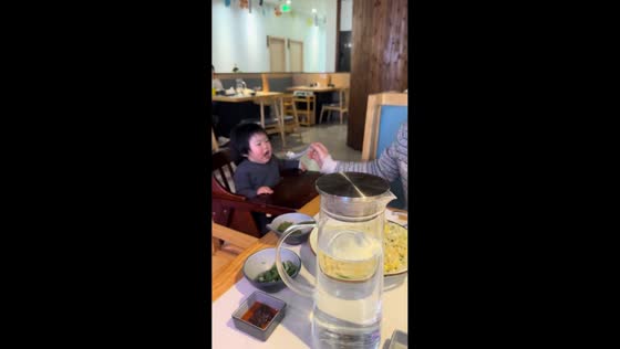 Toddler struggles to reach spoon while parent looks at phone in Jiangsu, China