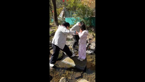 Woman slips and falls into stream while crossing on rocks in Heilongjiang, China