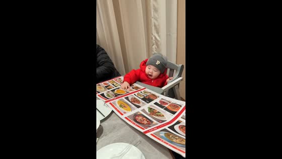 Baby pretends to eat from menu at the restaurant in Henan, China 