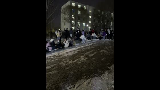 Students sliding down a frozen slope in Qinghai, China