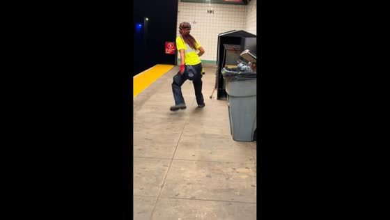 Cleaning worker cautiously opens garbage bin at underground train station in Manhattan, USA