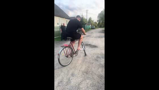 Man struggles to pedal bicycle until friend helps in Belitsa, Belarus