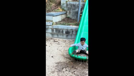Toddler slides into a muddy puddle at the bottom of a playground slide in Zhejiang, China