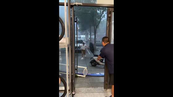 Woman loses balance in strong wind during rain in Shandong, China