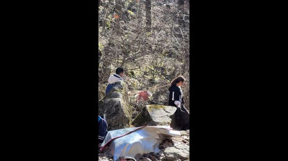 Hikers carry small dog on stick down mountain in Shaanxi, China