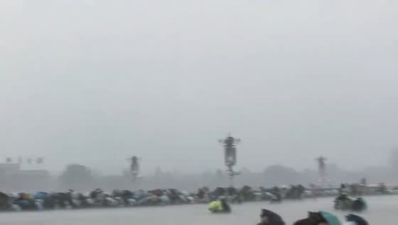 People shelter together during heavy rainstorm at Tiananmen Square in Beijing, China