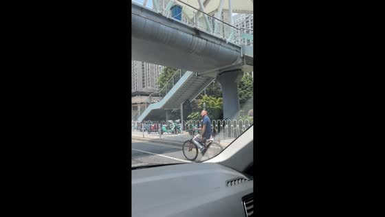 Elderly cyclist balances water bottle while overtaking in Hunan, China