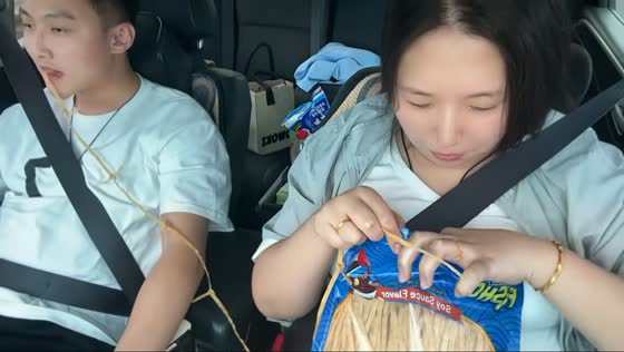 Woman ties Fisho Soy Sauce Flavor snack while man eats during drive in Liaoning, China