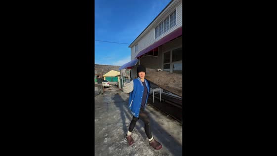 Woman slips while carrying log after posing for camera in Aydagulovo, Russia