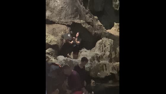 Lady with laptop stands in water during vacation in Hinagdanan Cave