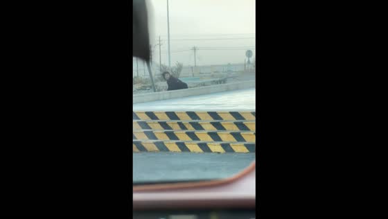 Woman struggles to walk against powerful winds and trips over a wall in Xinjiang, China