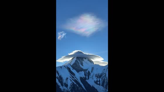 Hikers amazed by colorful lenticular cloud forming above a snow-capped mountain in Sichuan, China