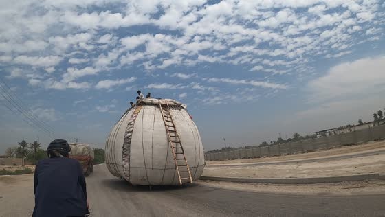 Overloaded tractor-taxi amuses onlookers on Karachi highway