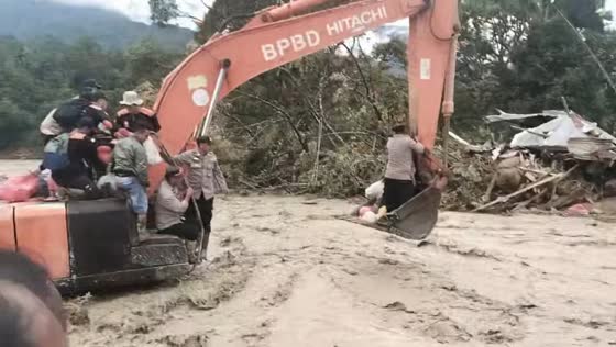 Aid workers use excavator to cross hazardous floodwaters in Sumatra, Indonesia