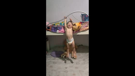 Baby laughs while climbing and hanging from bunk bed rail in Turin, Italy