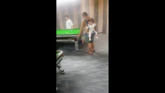 Father plays billiards with sleeping baby on his back in Guizhou, China