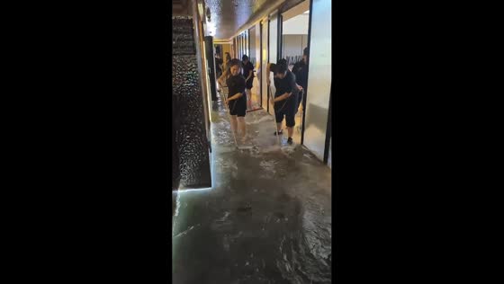 Workers clear floodwater from business establishment in Shanghai, China