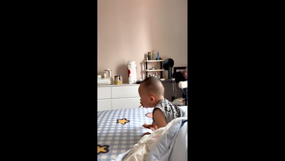 Cat blocks toddler from crawling toward edge of bed in Anhui, China