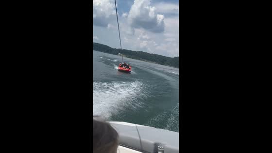 Three women flip off towable tube during lake outing in Wellington, Kentucky, USA