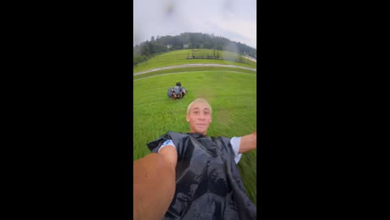 Friends slide down grassy slope with garbage bag in Augusta, Georgia