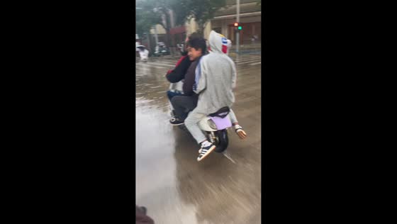 Three riders slide off motorcycle on wet road in Yunnan, China