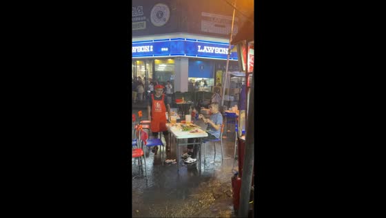 Man enjoys drink in the rain at night market in Liaoning, China